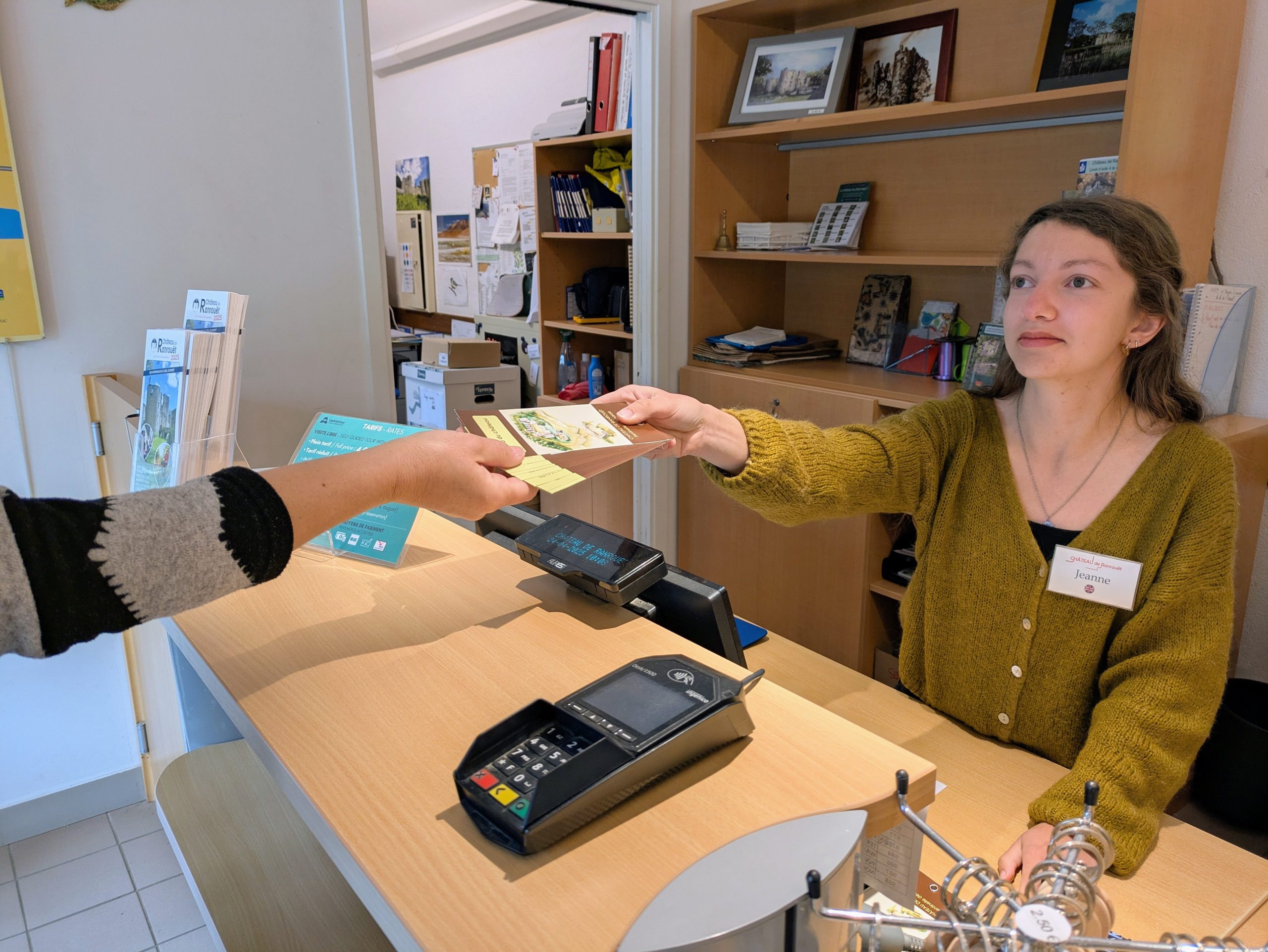 Médiatrice tendant un support de médiation à un visiteur à l’accueil du château.